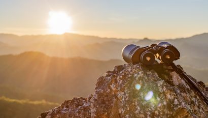 binoculars-on-top-of-rock-mountain-at-beautiful-sunset-background