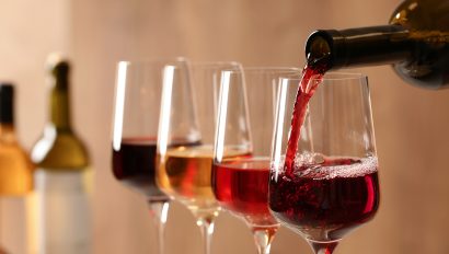 pouring-wine-from-bottle-into-glass-on-blurred-background-close