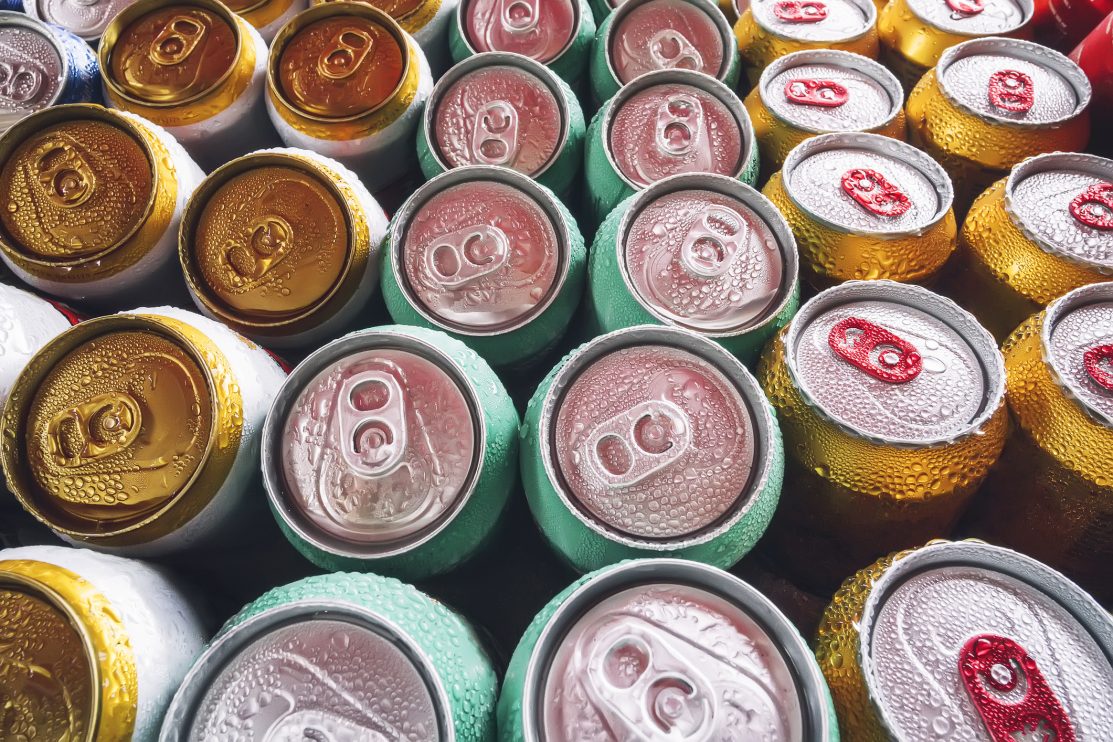 lots-of-aluminum-cans-in-the-ice-in-the-open-fridge-drops-of-water-on-a-cold-can-of-drink-metal-cans-of-beer-with-ice-cubes-in-mini-refrigerator-close-up