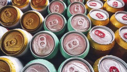 lots-of-aluminum-cans-in-the-ice-in-the-open-fridge-drops-of-water-on-a-cold-can-of-drink-metal-cans-of-beer-with-ice-cubes-in-mini-refrigerator-close-up