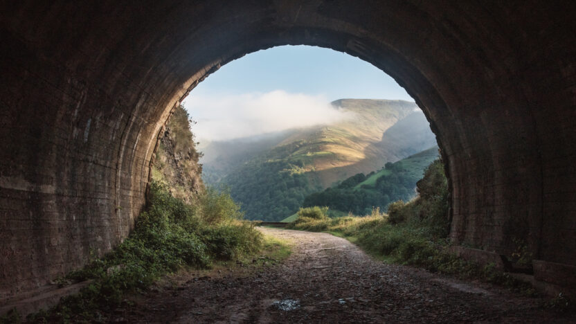 An old, dark tunnel leading to a beautiful landscape