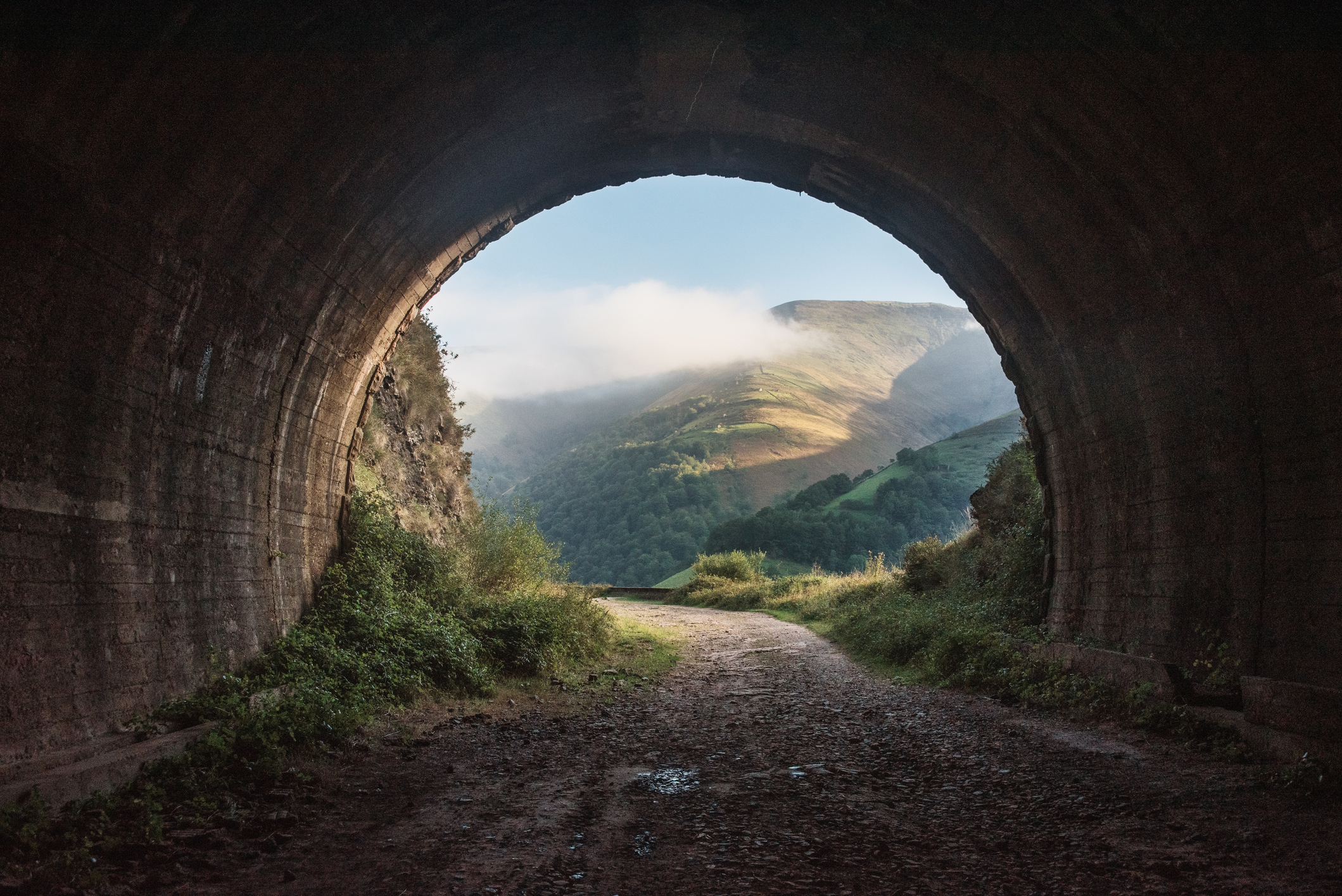 An old, dark tunnel leading to a beautiful landscape