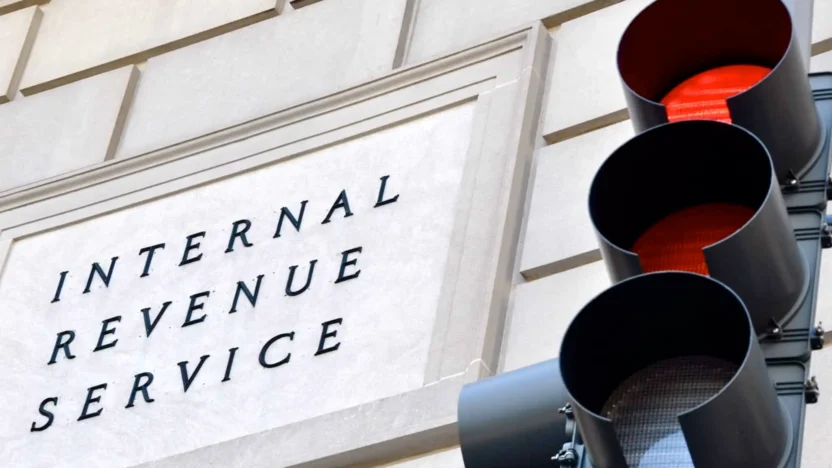 Internal Revenue Service sign with a traffic signal in the foreground indicating a red light.