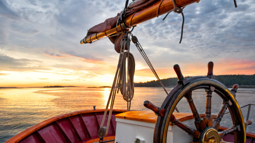 Steering wheel of sailboat navigating the waters at sunset