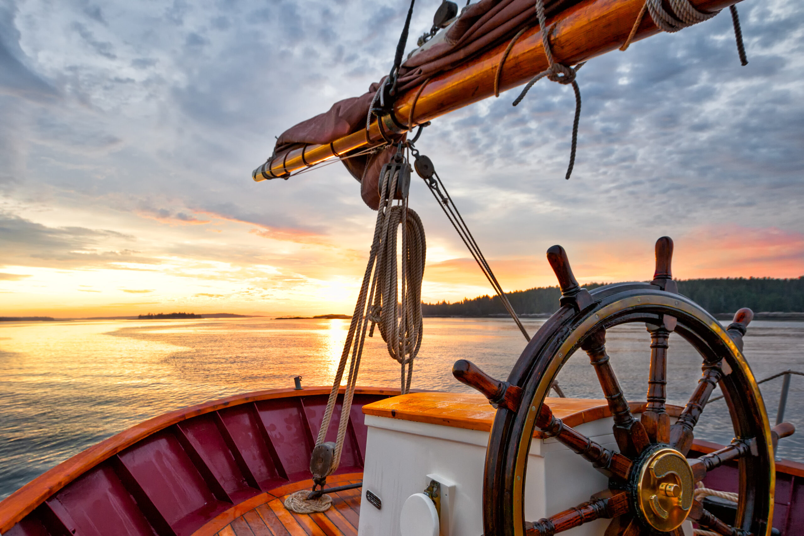 Steering wheel of sailboat navigating the waters at sunset