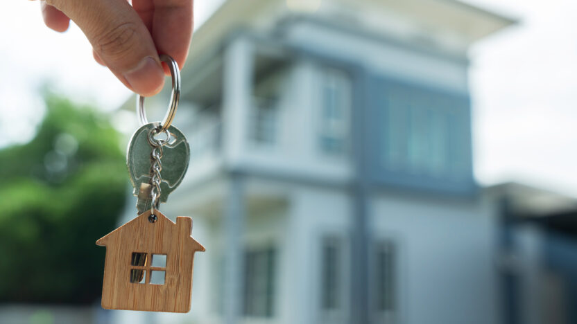 Person holding keys in shape of a house in front of a rental property